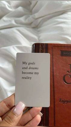 a person holding up a book with the words my goals and dreams become my reality