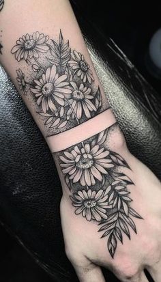 a black and white flower tattoo on the left hand, with an arrow in the middle