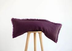 a purple pillow sitting on top of a wooden stool