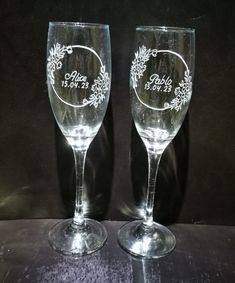 two wine glasses sitting on top of a table next to each other, with the names and date printed on them