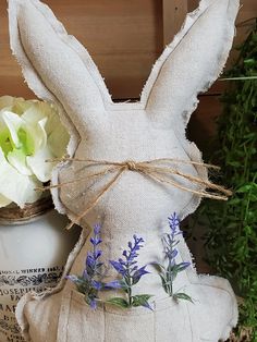 a white bunny sitting on top of a table next to a vase filled with flowers