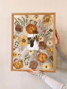 a woman holding up an art piece with flowers on it