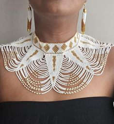 White gold African zulu necklace , African jewelry for wedding Zulu Shoulder necklace. This necklace is made using white & gold beads. Comes with matching earrings. Perfect for weddings or African themed events. **Buy multiple items and pay shipping for 1 item only.The rest ships free. More neckleces here; https://www.etsy.com/shop/TribalTess?ref=seller-platform-mcnav§ion_id=21306083 Back to my shop; https://www.etsy.com/shop/TribalTess?ref=seller-platform-mcnav Zulu Necklace, Jewelry For Wedding, Shoulder Necklace, Necklace African, Themed Events, African Jewelry, Zulu, Gold Beads, Matching Earrings