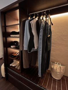 an open closet with clothes and shoes hanging on the rack, next to a handbag