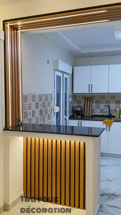 a kitchen with white cabinets and black counter tops is seen through a mirror on the wall