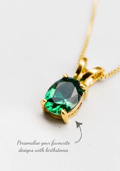 a necklace with an emerald colored stone on the front and back of it's chain