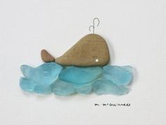 a rock and some blue sea glass on a white surface with a hook in the middle