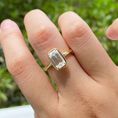 a woman's hand with a ring on it that has an emerald stone in the middle