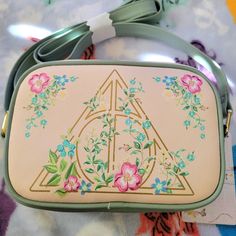 a small purse with a triangle and flowers painted on the front, sitting on top of a table