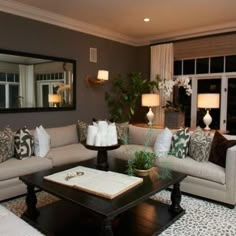 a living room with couches, tables and lamps on the floor in front of windows