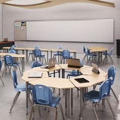 an empty classroom with desks and laptops