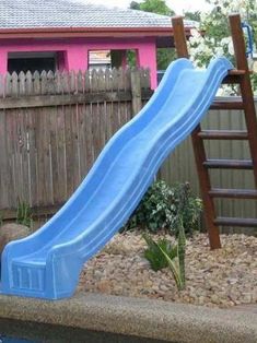 a blue slide sitting next to a wooden fence