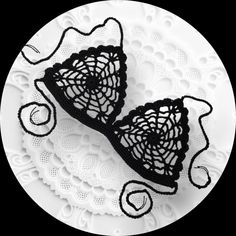 two black crocheted bras sitting on top of a white doidled plate