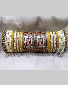 Make A Bold Statement With This Yellow & White Photo Chura Set. Beautified With High Quality Glass Stone Beaded. Photo Kada Is Prettified With Rajwadi Style Hand Painting Meenakari And High Quality Glass Kundan Fitting. Be An Angel And Create A Splendid Impact On Everyone By Wearing This Gorgeous Design. This is a set of 30 Bangles (15 For Each Hand). Note: We Can Put Your Picture Into The Frame On Center Bangle. Simply Send Us Your Picture After Ordering It. Festive White Bridal Sets For Marriage, White Kundan Jewelry For Wedding And Festivals, Yellow Cutdana Jewelry For Wedding, White Bridal Sets For Ceremonial Festive Occasions, Festive White Bridal Sets For Ceremonial Occasion, White Bridal Sets With Zari Work For Festive Occasions, Festive White Bridal Sets With Zari Work, White Cutdana Bridal Sets For Wedding, White Traditional Wear For Marriage And Festivals