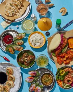 a table topped with plates and bowls filled with different types of food next to drinks