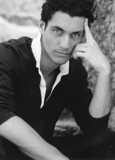 a young man poses for a black and white photo