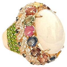 Bochic "Flamenco” Opal & Multi Fancy Color Sapphires Cocktail Ring 18K Gold Opal - 12 Carat Cluster Multi Color Fancy Gems from Sri Lanka 4 Carat Peridot - 1 Carat White Topaz 1 Carat Blue Sapphire - 1 Carat This Ring is from the "Flamenco” traveling collection are the epitome of elegance and versatility. It offers a perfect blend of day to night and swimwear to evening wear, allowing you to effortlessly transition between different occasions and outfits. Wearing these spectacular oriental-style Luxury Multicolor Cabochon Rings, Luxury White Multi-stone Gemstones, Elegant Multicolor Cabochon Rings, Luxury Multi-stone White Rings, Elegant White Cabochon Gemstones, Elegant White Gemstones With Accent Stones, Sapphire Cocktail Ring, Fancy Sapphire, Colored Gems