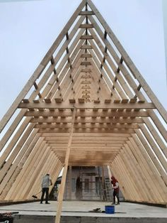 two men working on a wooden structure in the middle of a construction area with ladders