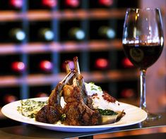 a plate of food and a glass of wine on a table in front of some bottles