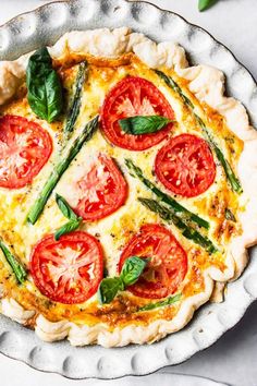 a quiche with tomatoes and asparagus in a pie pan on a table