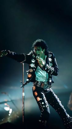 michael jackson performing on stage with his microphone in hand and wearing black leather pants,