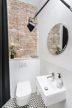 a white toilet sitting next to a bathroom sink under a black and white wall mounted mirror