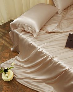 a bed with white sheets and pillows on top of it next to a small vase