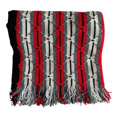 a red, black and white blanket with fringes on the ends is shown in front of a white background