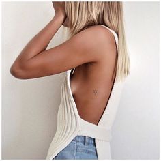 the back of a woman's head with her hand on her hair and wearing a white tank top