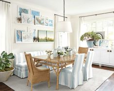 a dining room table with chairs and pictures on the wall above it, along with potted plants