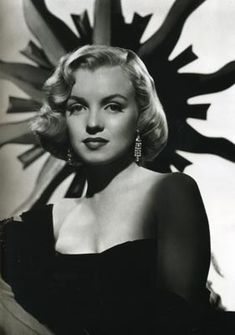 an old black and white photo of a woman in a dress with large earrings on her head