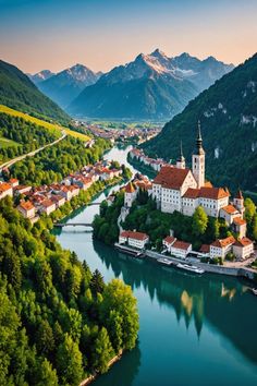 an aerial view of a small town in the middle of a river with mountains in the background