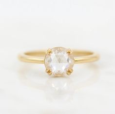 a yellow gold ring with an oval shaped white topazte stone in the center