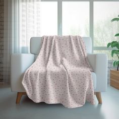 a white chair with a pink blanket on top of it next to a potted plant