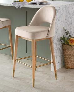 two beige stools sitting in front of a marble counter top with flowers on it