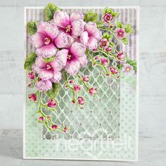 a card with pink flowers and green leaves on the front, sitting on a table