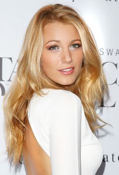 a woman with blonde hair wearing a white dress and posing for the camera at an event