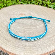 a blue string bracelet on top of a tree stump