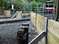 a train traveling down tracks next to a wooden rail road bridge with metal railings