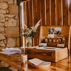 an open suitcase sitting on top of a wooden table next to a vase filled with flowers