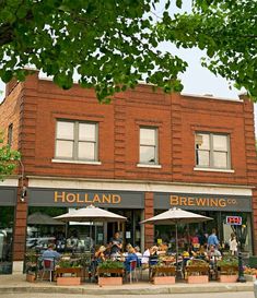 people are sitting at tables in front of a brick building with an awning on it