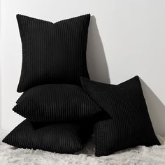 two black pillows sitting next to each other on top of a white carpeted floor