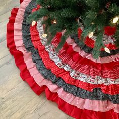 a christmas tree skirt made out of red and black ruffles on a wooden floor