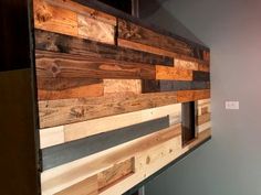 a wall made out of wooden planks in a room with gray walls and grey flooring