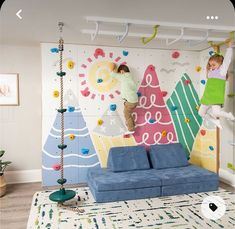 two children climbing up the side of a wall with colorful decorations on it and hanging from hooks