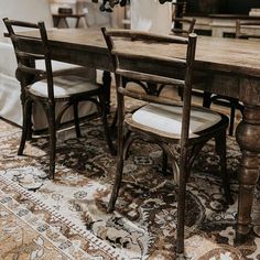 a dining room table with chairs and a rug on the floor in front of it