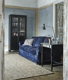 a living room with a blue couch, table and glass cabinet in it's corner