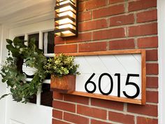 a house number sign mounted to the side of a brick building next to a potted plant