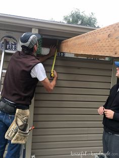 two men are working on the roof of a house that is being built with wood planks