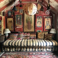 an old fashioned couch in a room with many pictures on the wall and lamps hanging from the ceiling